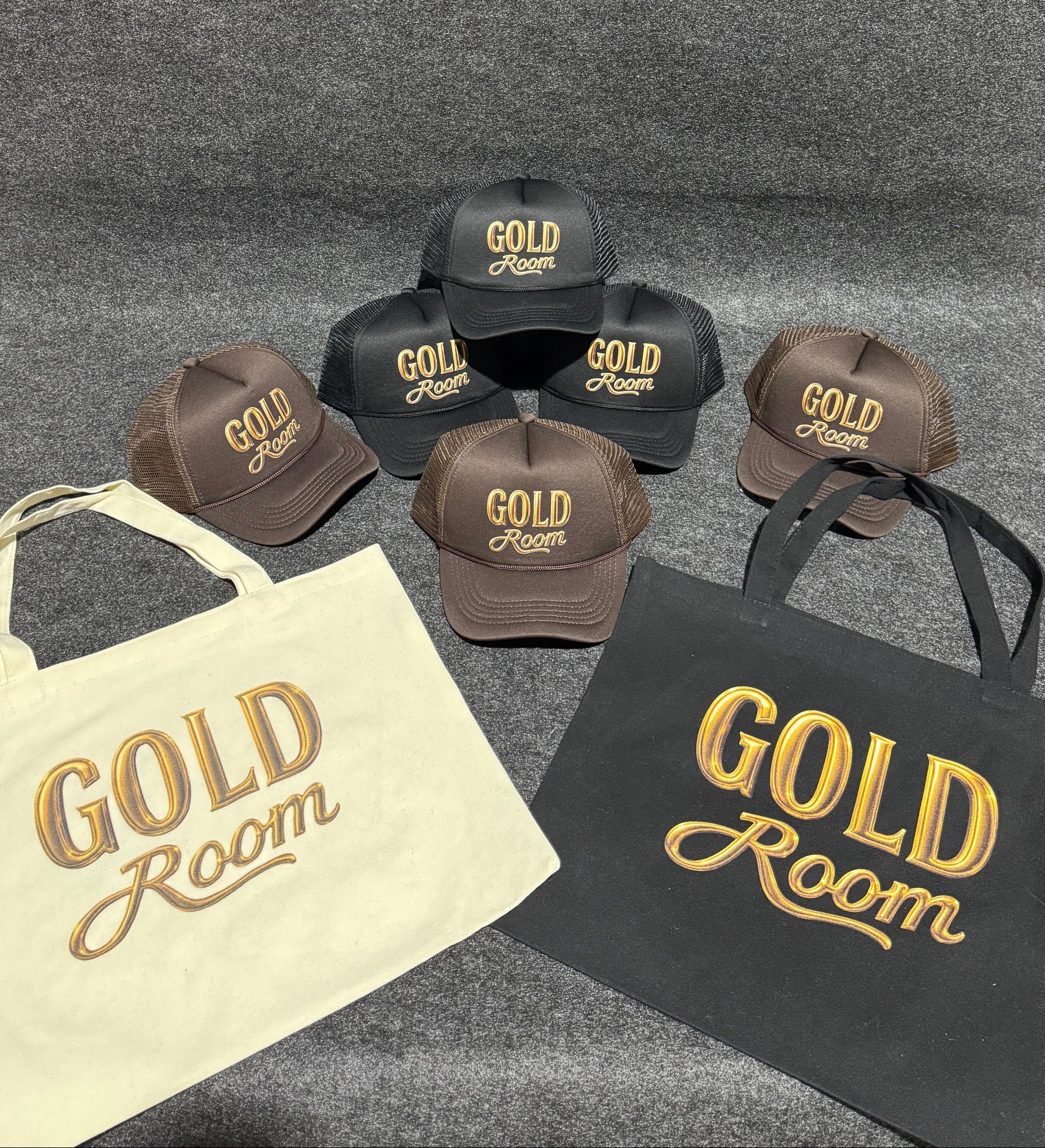 Brown hats and a beige tote bag with 'Gold Room' branding on a gray surface.